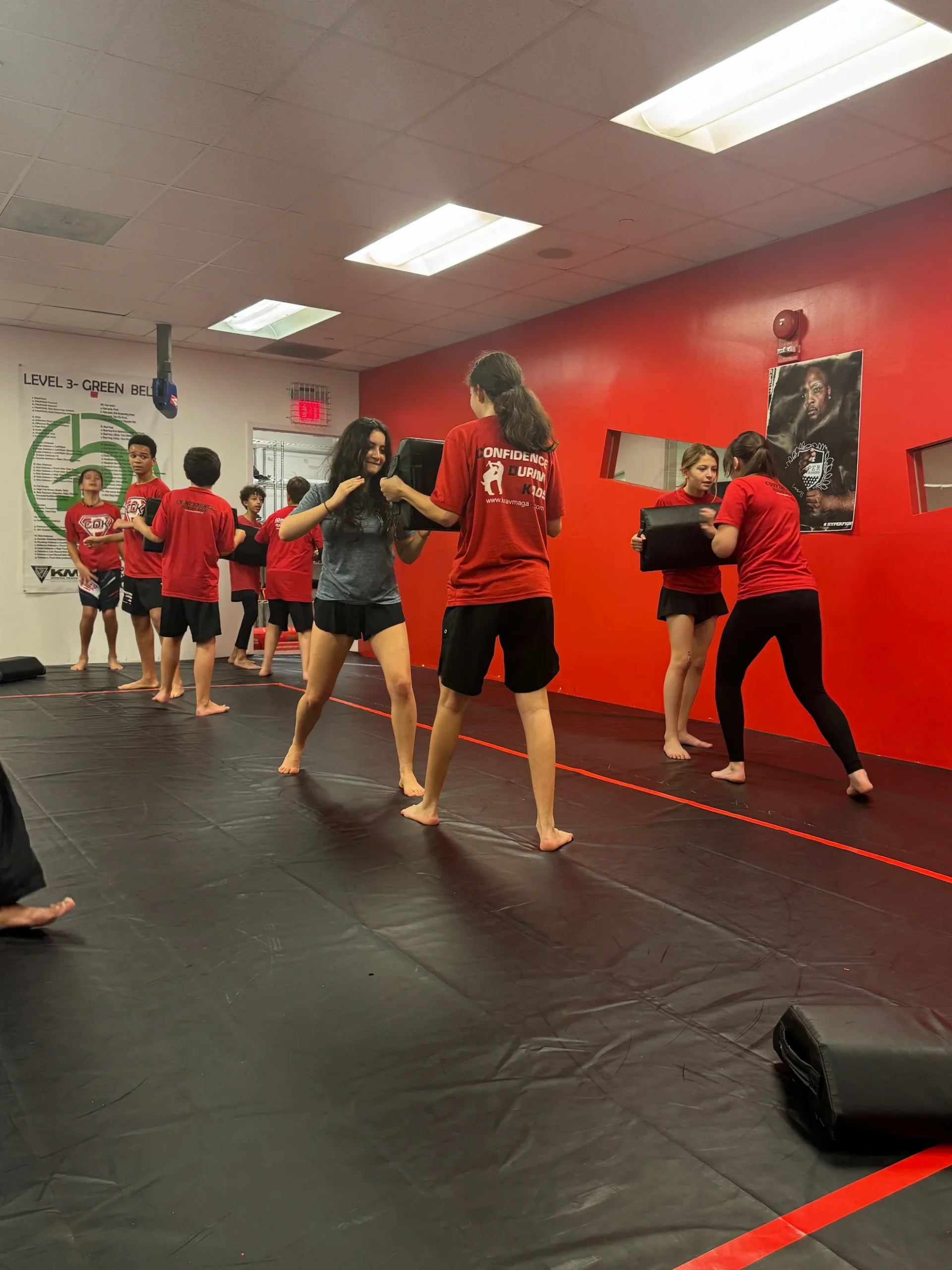 Teen students practicing partner pad drills during a self-defense and fitness class in Bethesda, Maryland.